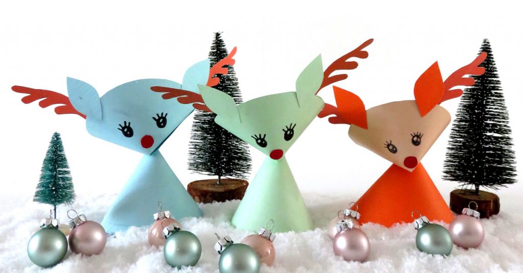 Three handmade paper reindeer in Christmas setting.