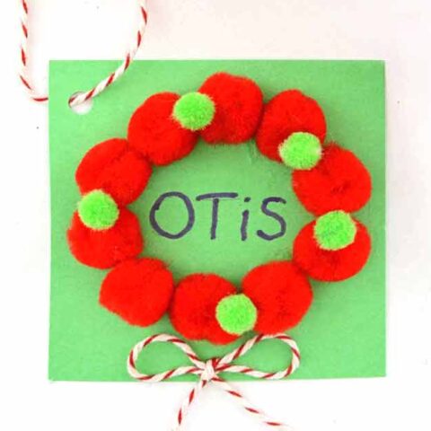 DIY mini pom pom Christmas wreath gift tag in red and green.