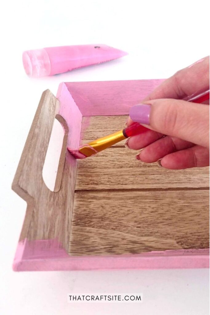 Wood serving tray sides being painted in pink.