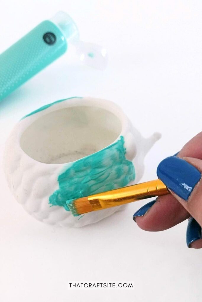 White planter being painted in turquoise blue.